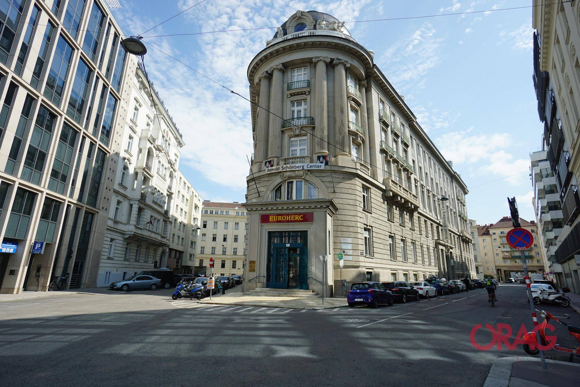 Historisches Eckgebäude mit klassischer Architektur und belebter Straßenansicht in der Stadt.