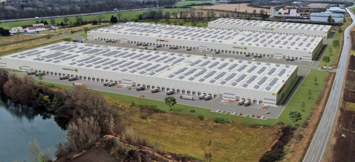 Übersicht des Logistikparks mit modernen Lagerhallen, Solaranlagen und angrenzenden Feldern und einem See.