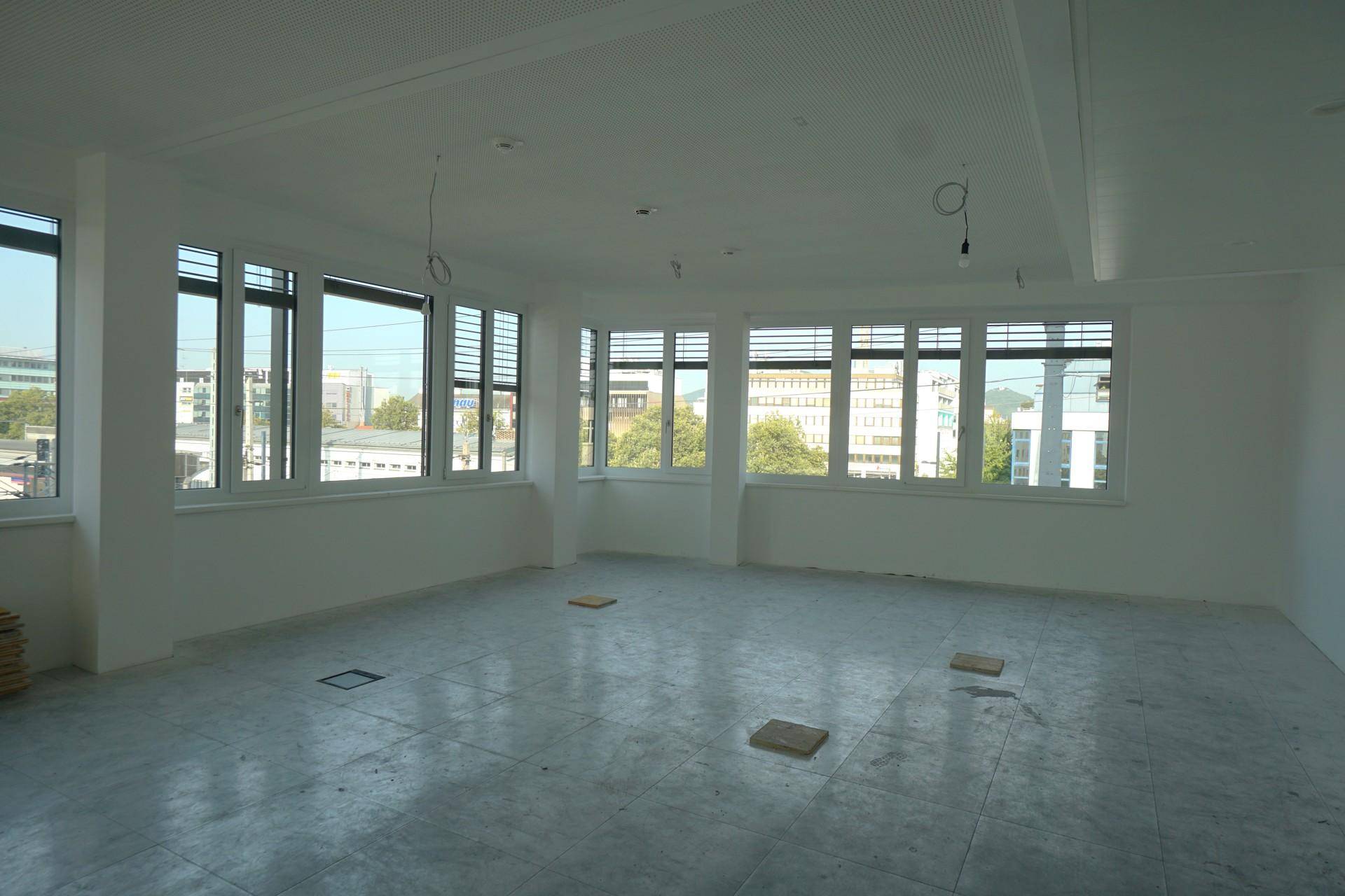 Heller Büroraum mit Fliesenboden und weitem Blick auf die städtische Umgebung.