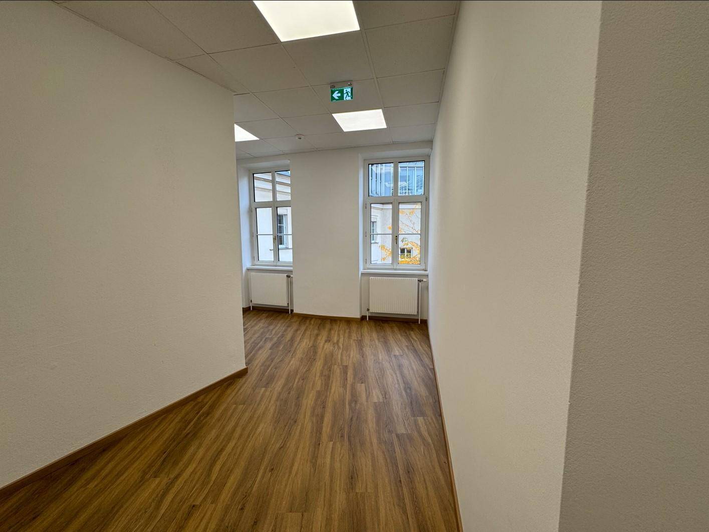 Heller Flur mit Laminatboden und Fenstern, die Tageslicht in den Raum lassen.