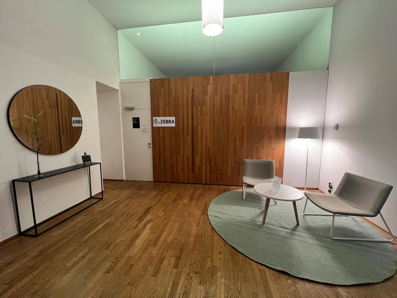 Empfangsbereich mit Holzboden, runden Spiegeln und minimalistischen Sitzgelegenheiten für Besucher.