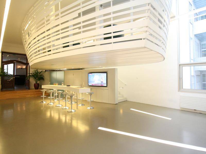 Großer, offener Loungebereich mit hoher Decke, einer Bar und einer schwebenden Galerie im modernen Design.