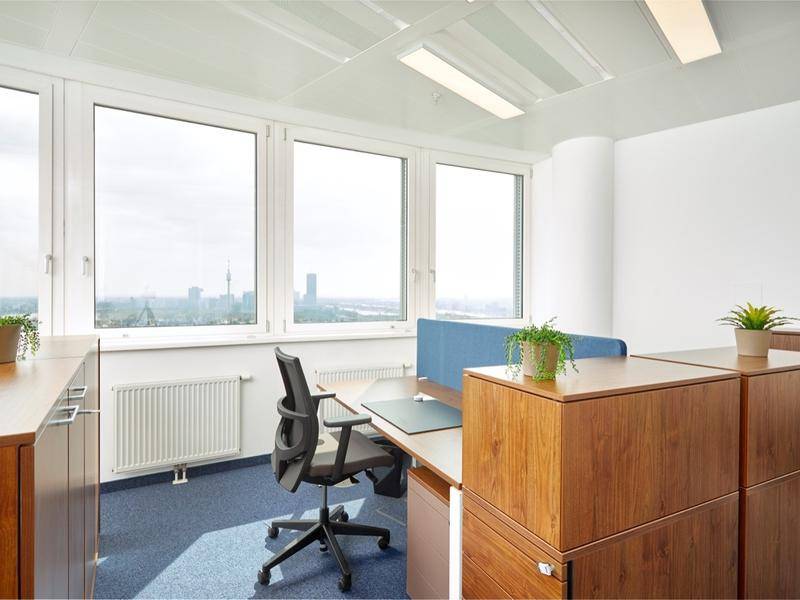 Moderner Arbeitsplatz mit Holzmöbeln, ergonomischem Stuhl und Blick auf die Stadt.