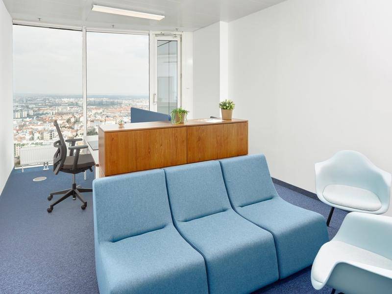 Offener Bürobereich mit blauen Sofas, Holzschrank und weitem Stadtblick.