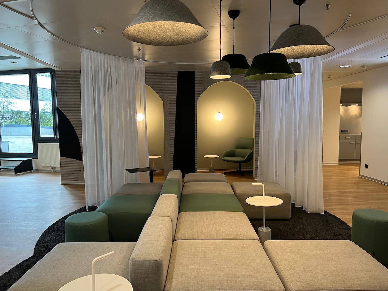 Stilvoller Lounge-Bereich mit modularen Sofas, Vorhängen und dekorativen Nischen.
