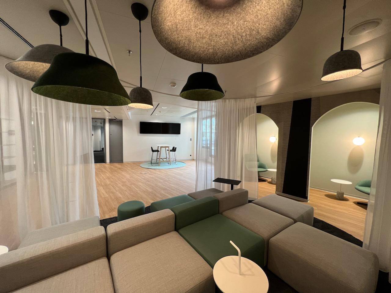 Großer Lounge-Bereich mit modularen Sofas, dekorativen Lampen und Holzboden.