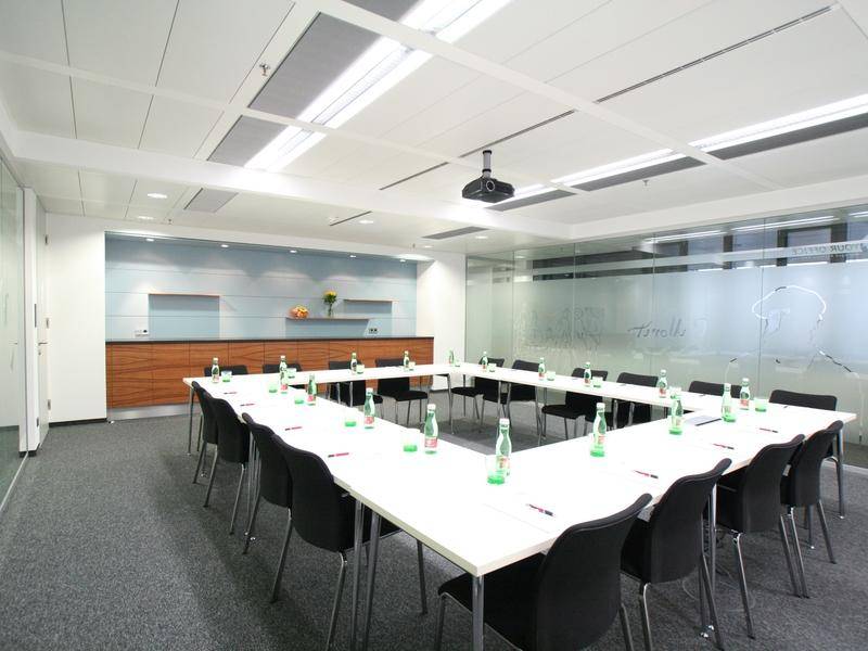 Großer Konferenzraum mit U-förmiger Tischordnung, Beamer und Glaswand.
