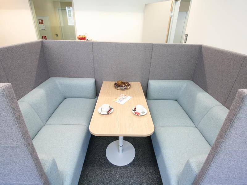 Gemütliche Sitznische mit gepolsterten Bänken und einem kleinen Holztisch.