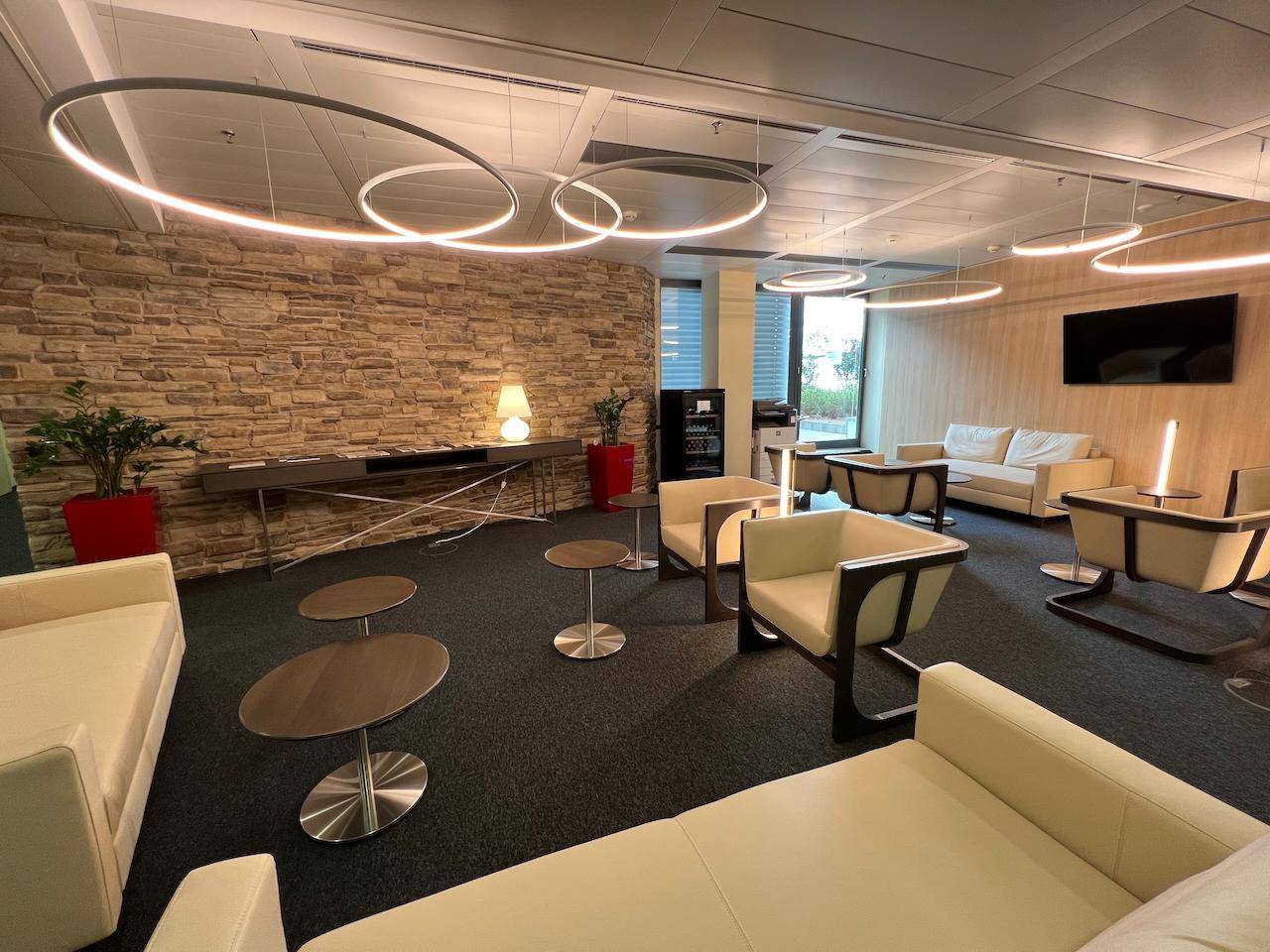Stilvoller Lounge-Bereich mit bequemen Sofas, Steinwand und modernen Beleuchtungselementen.