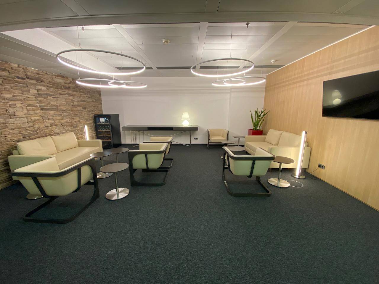 Gemütlicher Lounge-Bereich mit Steinwand, bequemen Sofas und modernen Ringlampen.