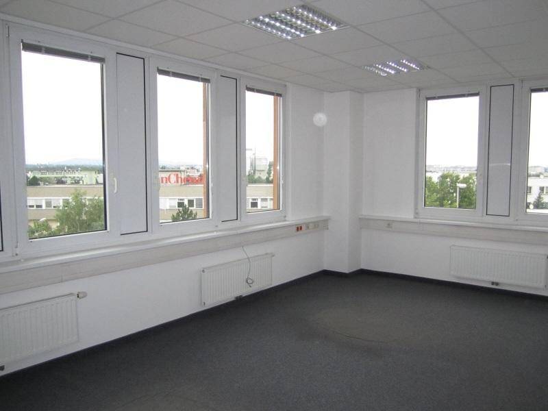 Leerer Büroraum mit großen Fenstern, die eine weite Aussicht bieten, und einem praktischen Teppichboden.