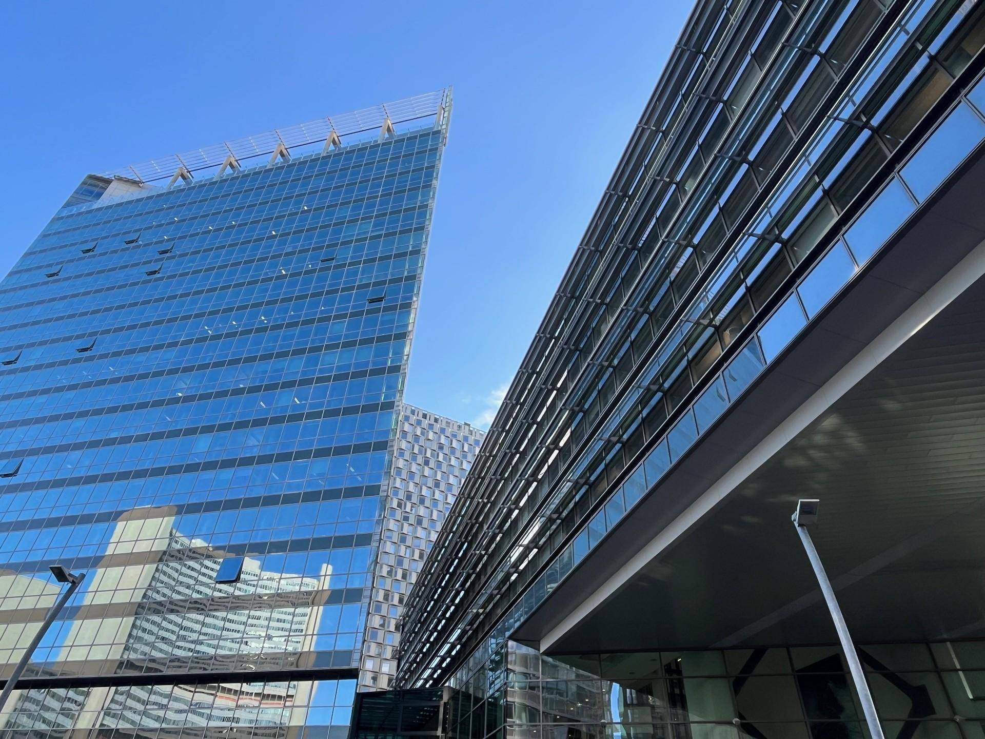 Moderne Hochhäuser mit Glasfassaden und zeitgenössischer Architektur unter blauem Himmel.