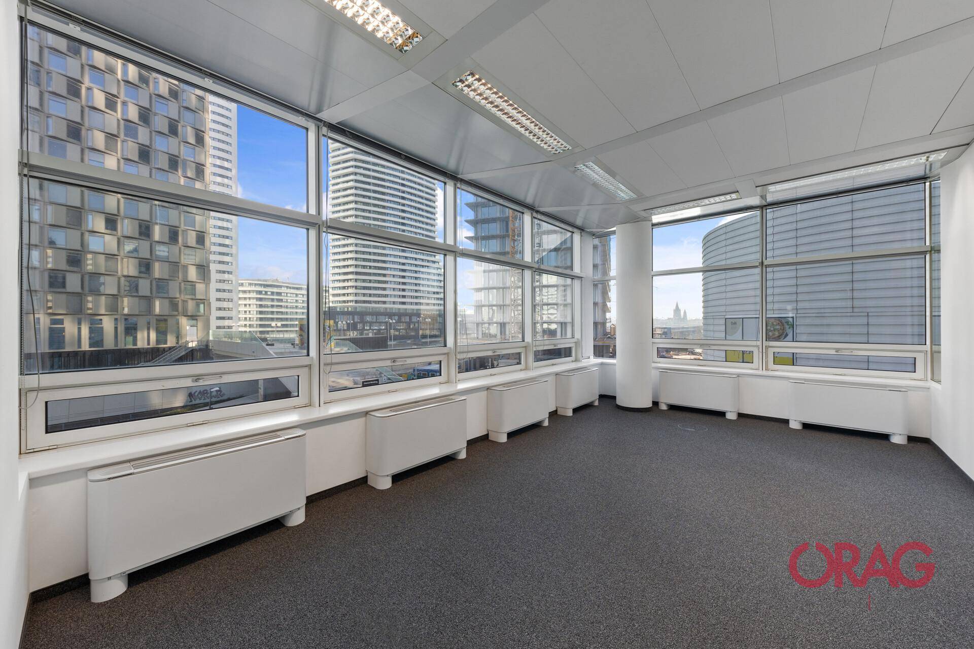 Geräumiges Büro mit Teppichboden und großen Fenstern, die einen weiten Blick auf die Stadt bieten.