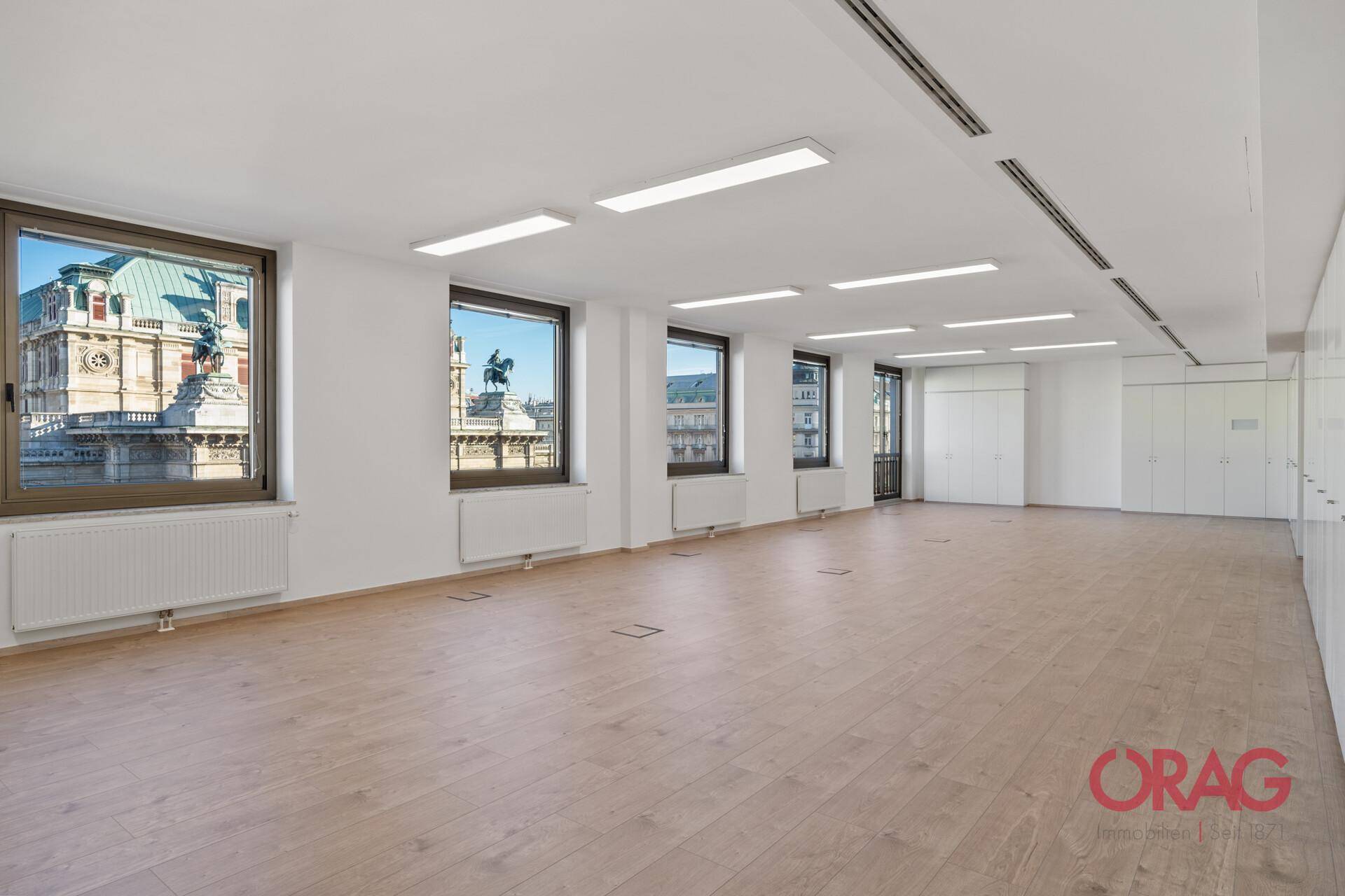 Großes, leeres Büro mit Holzboden, vielen Fenstern und einem beeindruckenden Blick auf die Wiener Staatsoper.