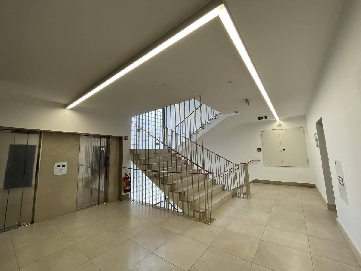 Heller Flur mit Steinboden, Treppe und Aufzügen, die zu den oberen Etagen des Gebäudes führen.