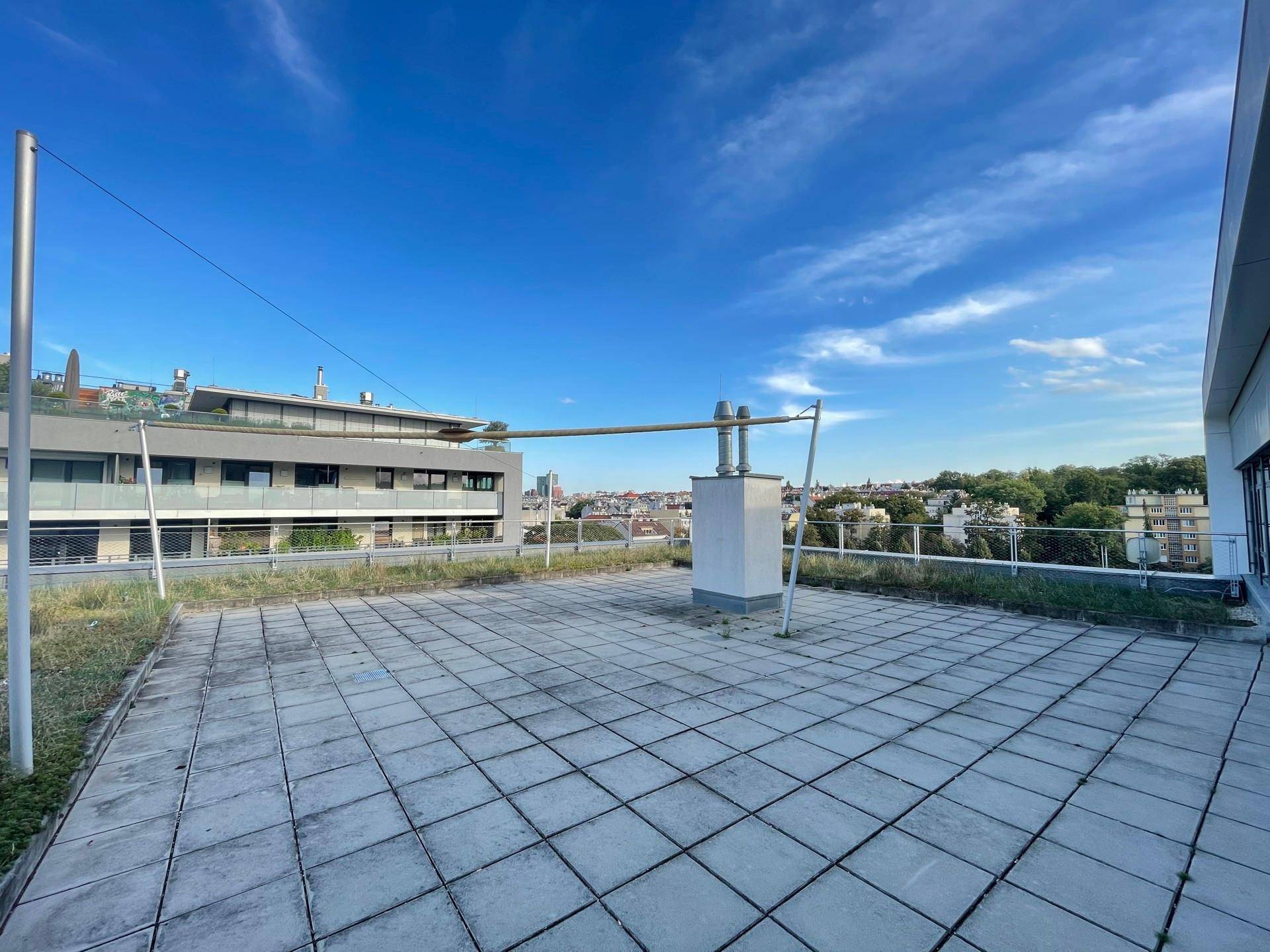 Große Dachterrasse mit Fliesenboden und weitem Blick über die Stadt und die umliegende Landschaft.