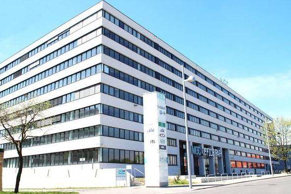 Großes Bürogebäude mit vielen Fenstern und moderner Architektur an einem sonnigen Tag.