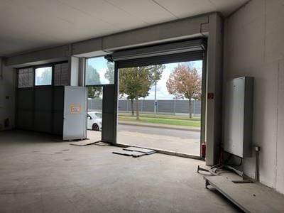Leerer Lagerraum mit großem Rolltor, viel Tageslicht und direktem Zugang zur Straße für Lieferungen.