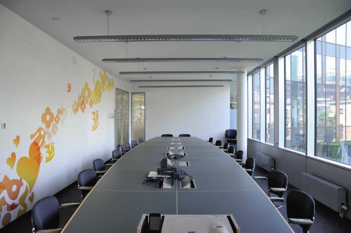 Großer Konferenzraum mit langem Tisch, vielen Stühlen und großen Fenstern für viel Tageslicht.