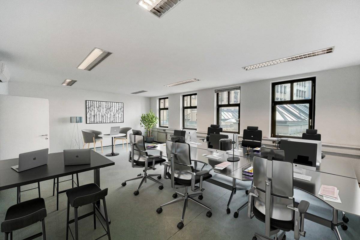 Großes, modern eingerichtetes Büro mit mehreren Arbeitsplätzen, Besprechungsbereich und vielen Fenstern. Die Beleuchtung ist hell.