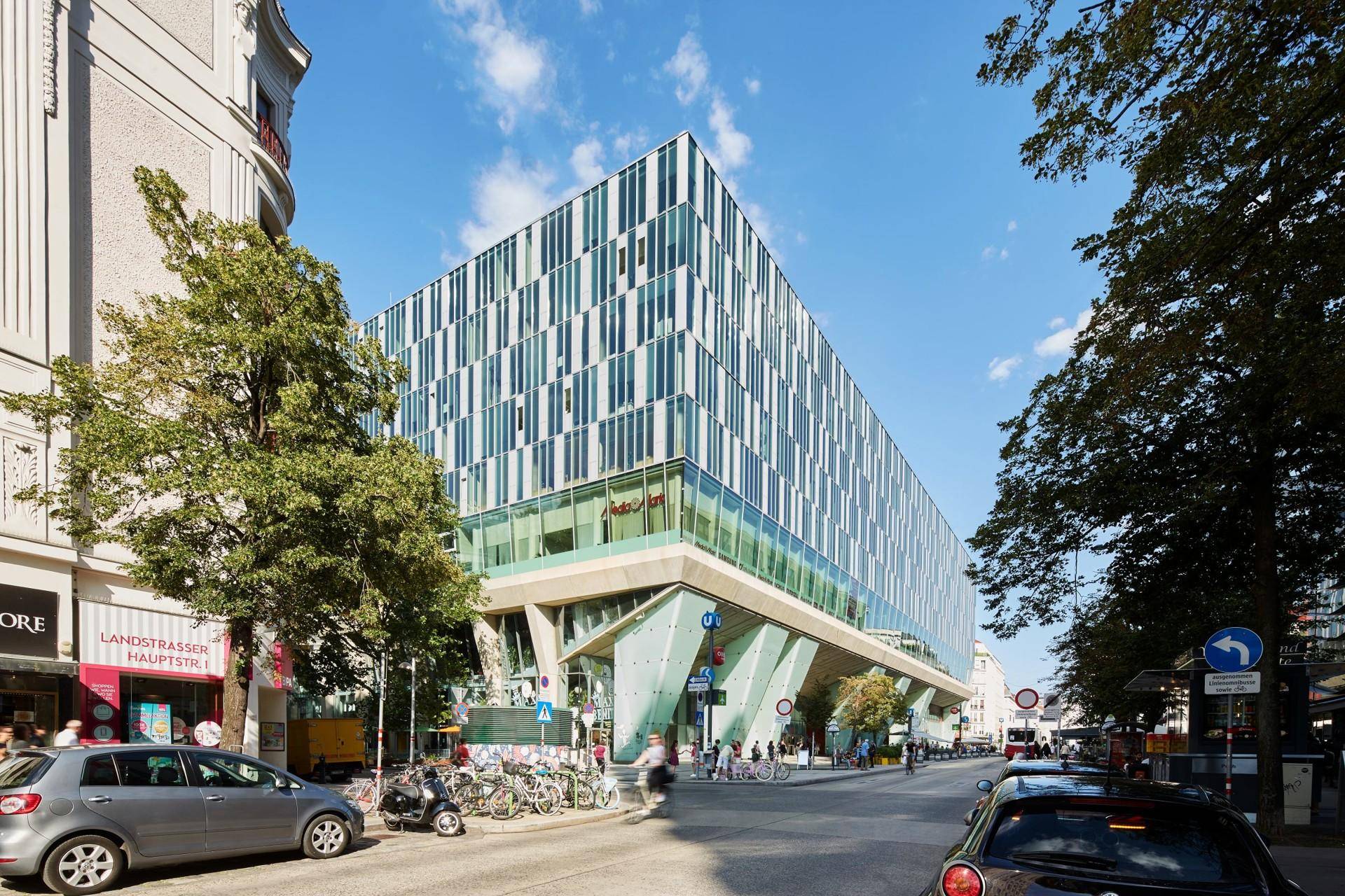 Moderne Architektur eines Geschäftsgebäudes mit markanter Fassade und großen Glasflächen an einer belebten Stadtstraße.
