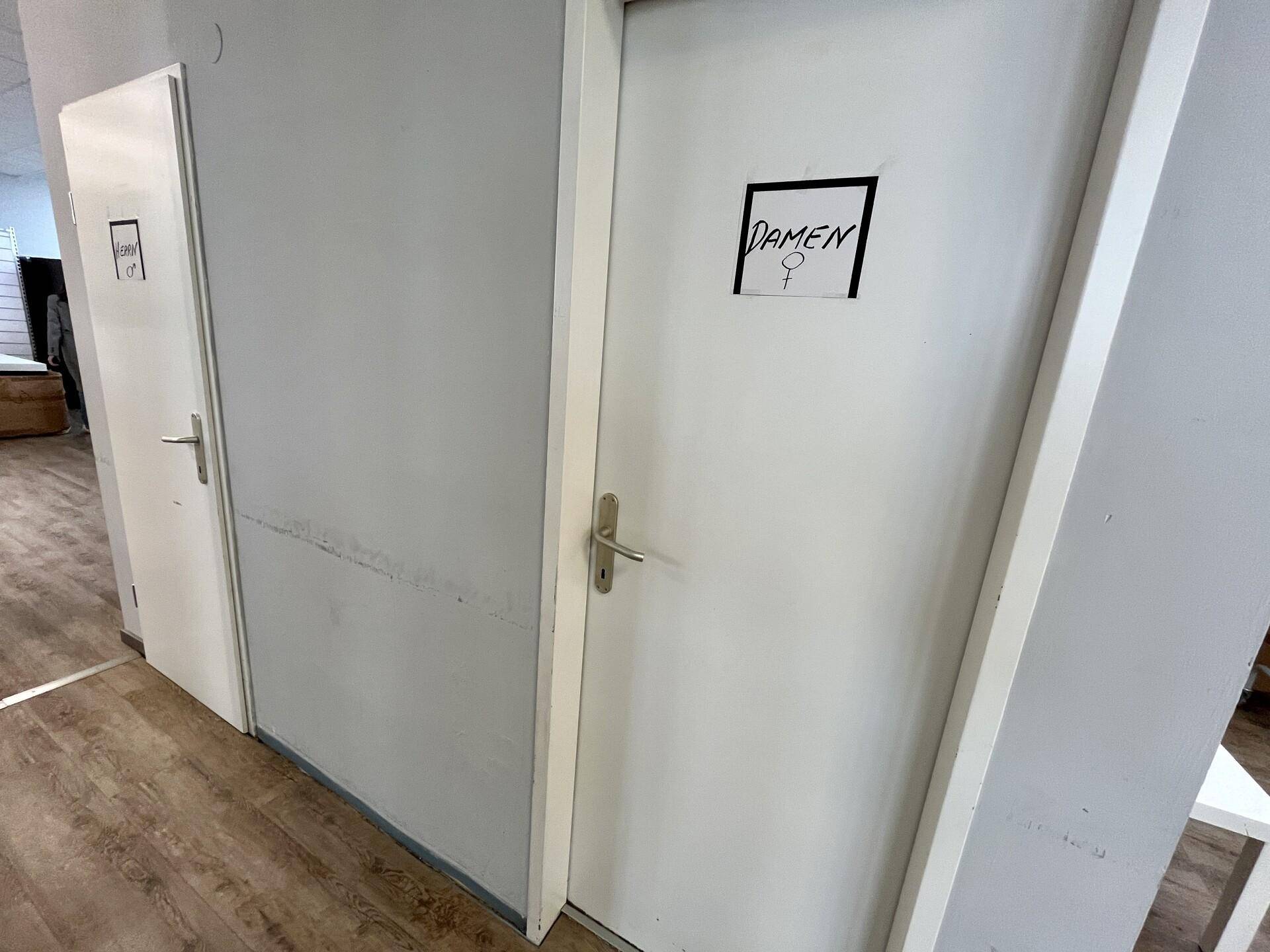 Flur mit zwei weißen Türen, eine davon als Damentoilette gekennzeichnet.