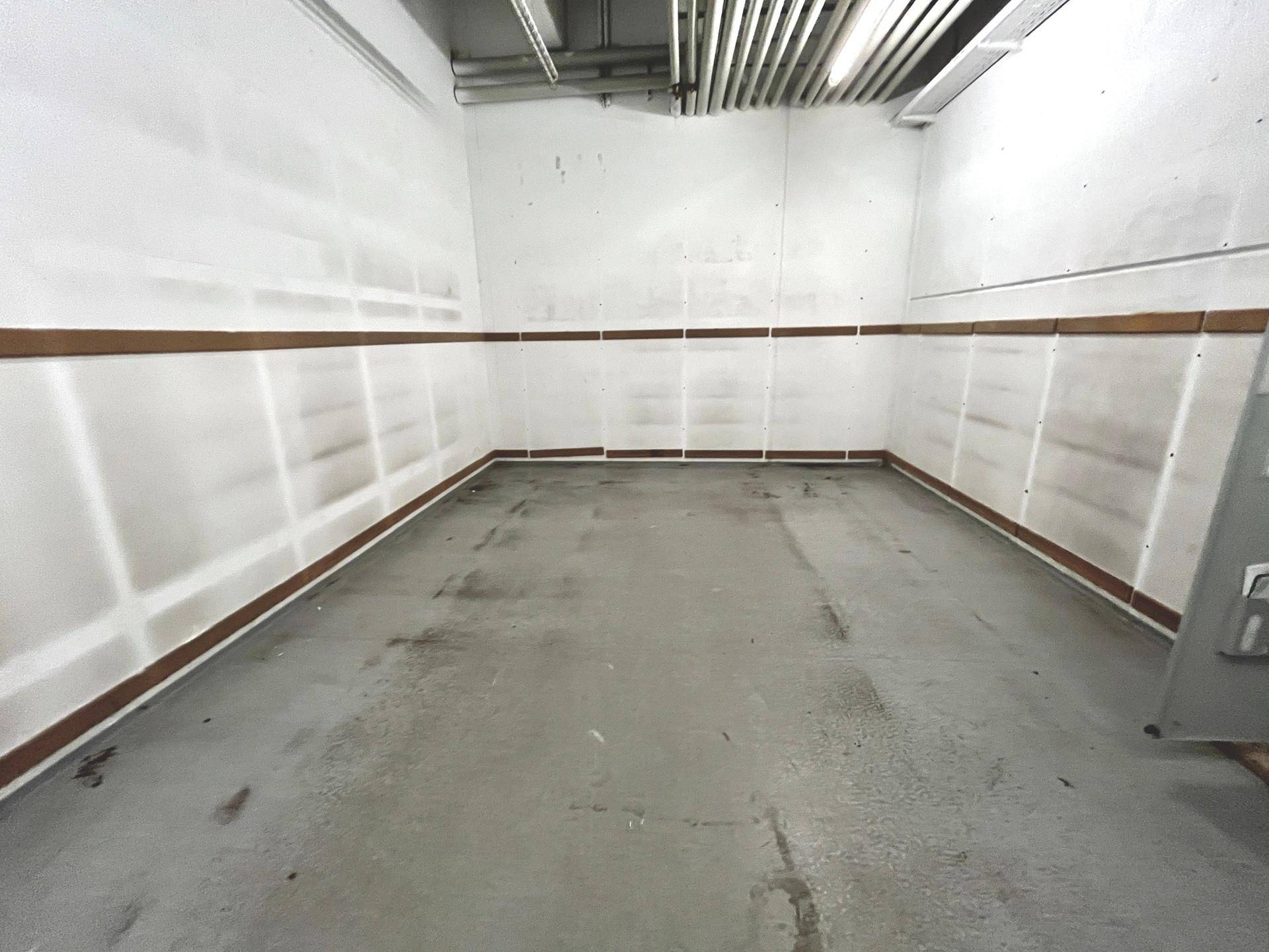 Leerer Lagerraum mit Betonboden und einfachen Wänden, ausgestattet mit sichtbaren Leitungen an der Decke.