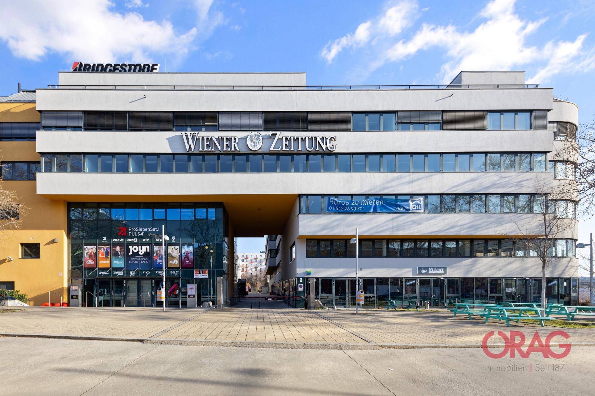 Moderne Geschäftsfassade mit großen Fenstern, prominenten Firmenlogos und einem einladenden Eingangsbereich.
