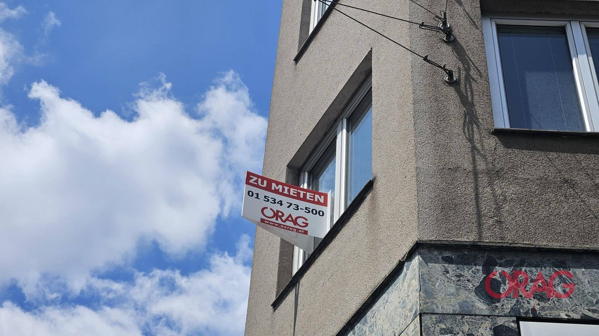 Nahaufnahme eines Gebäudes mit einem roten "Zu vermieten"-Schild an einem Fenster.