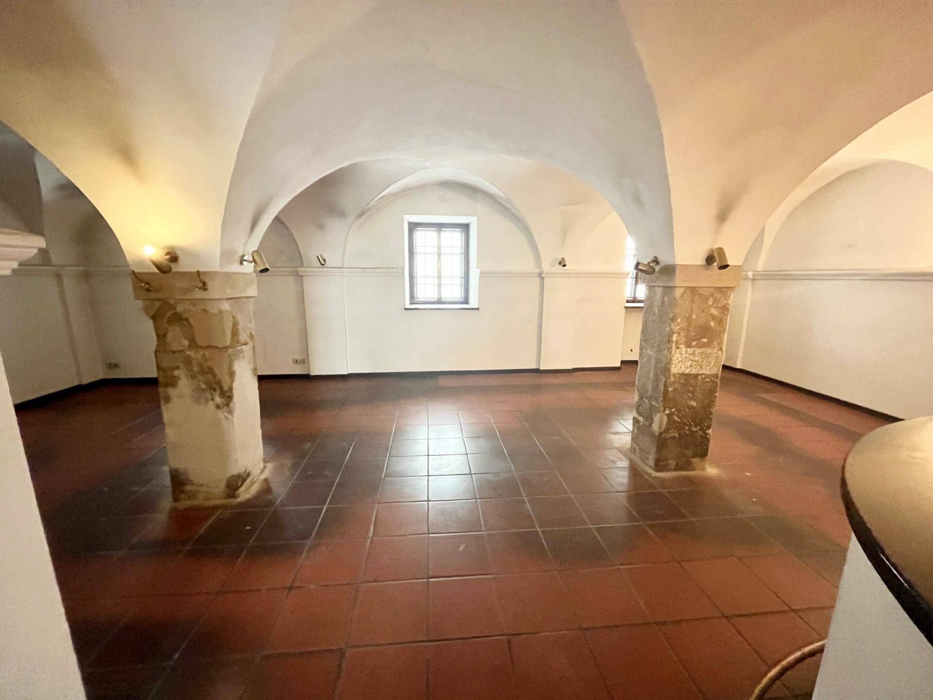 Geräumiger Gewölberaum mit Terrakottafliesen und einem Fenster, das Tageslicht hereinlässt.