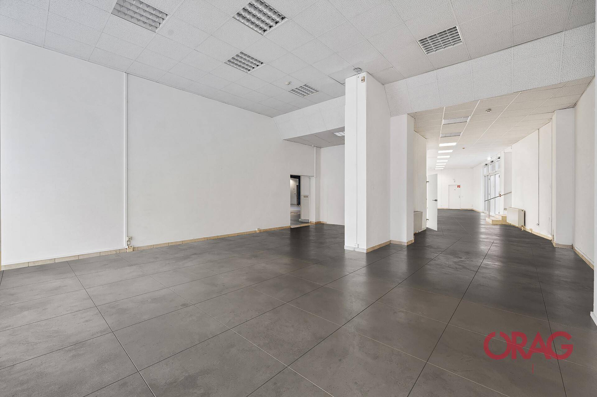 Großer, leerer Gewerberaum mit Fliesenboden und abgehängter Decke, bereit für die Gestaltung.