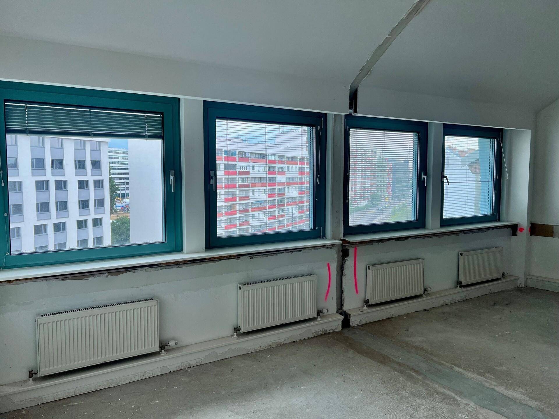 Detailansicht der Fensterfront mit Heizkörpern in einem Raum, der sich im Renovierungszustand befindet.