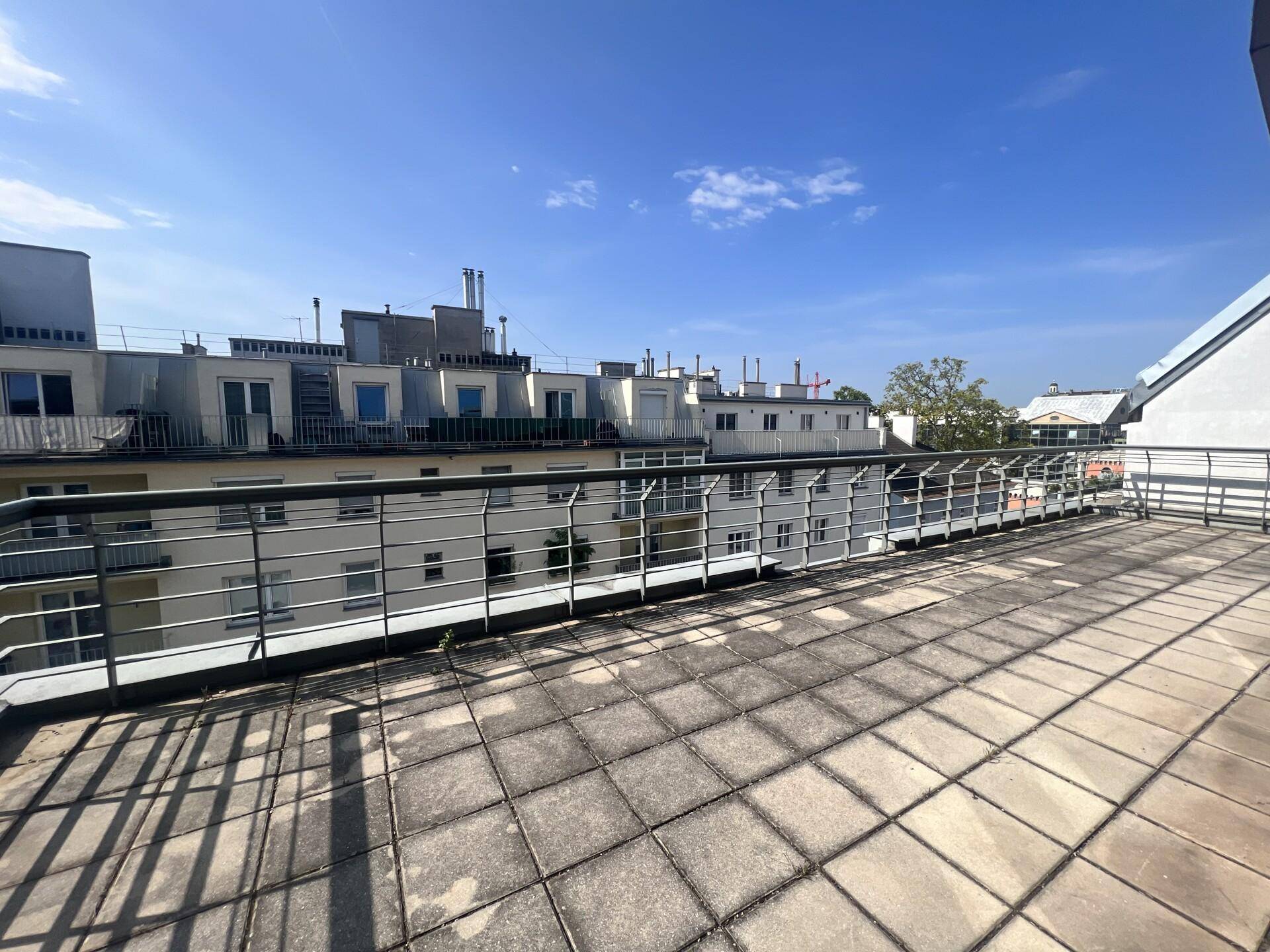 Große Dachterrasse mit Fliesenboden und weitem Blick über die Stadtlandschaft.