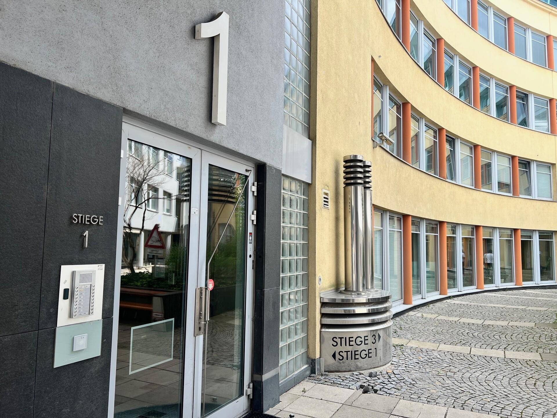 Eingangsbereich eines modernen Bürogebäudes mit Gegensprechanlage und geschwungener Fassade.