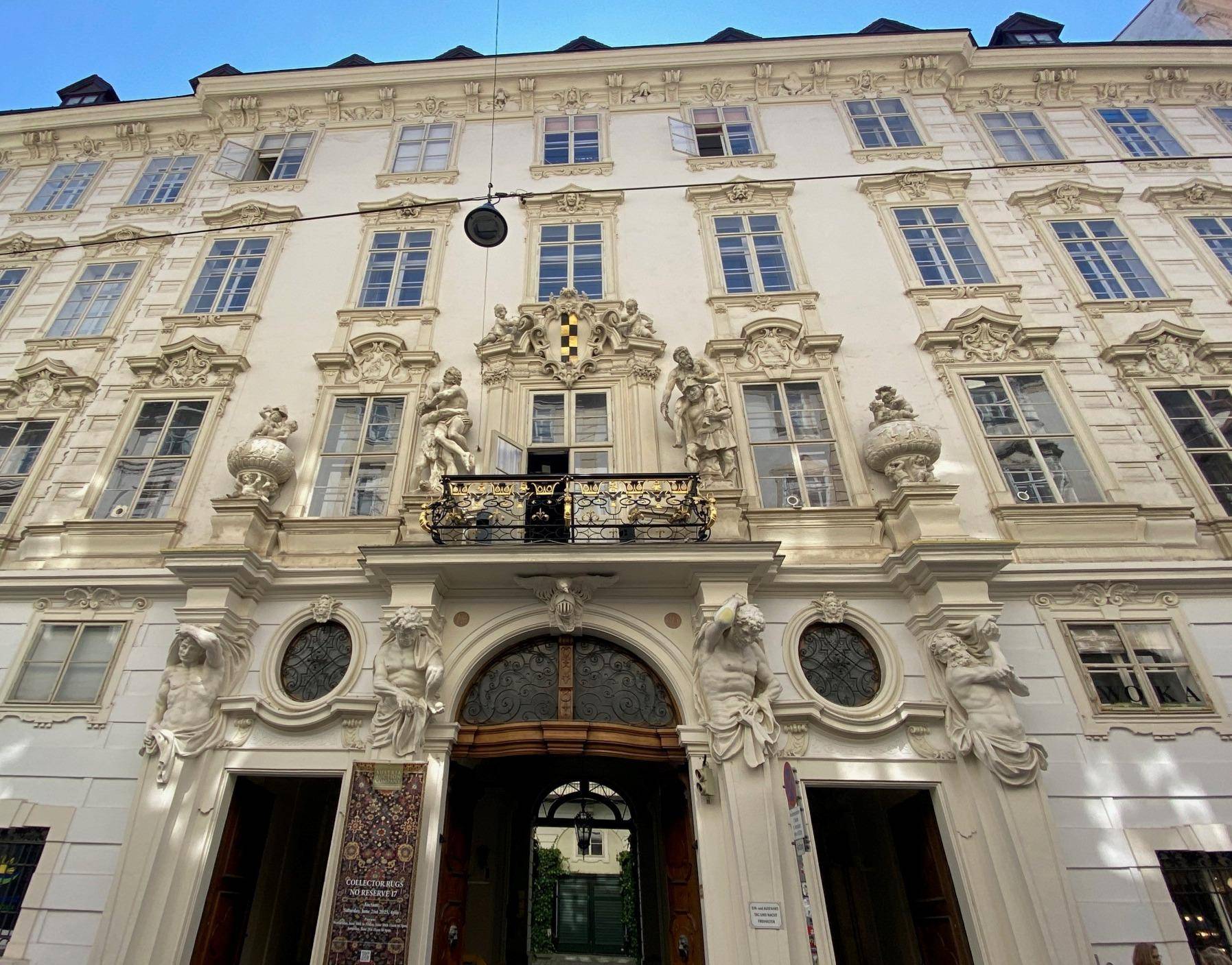 Prachtvolle historische Fassade mit aufwendigen Skulpturen, Verzierungen und einem kleinen Balkon.