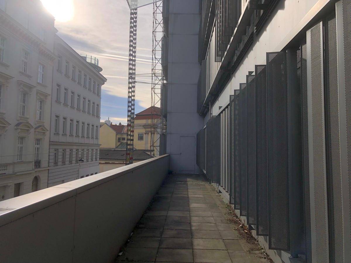 Langer, schmaler Balkon mit Metallgeländer und Blick auf die Stadt.