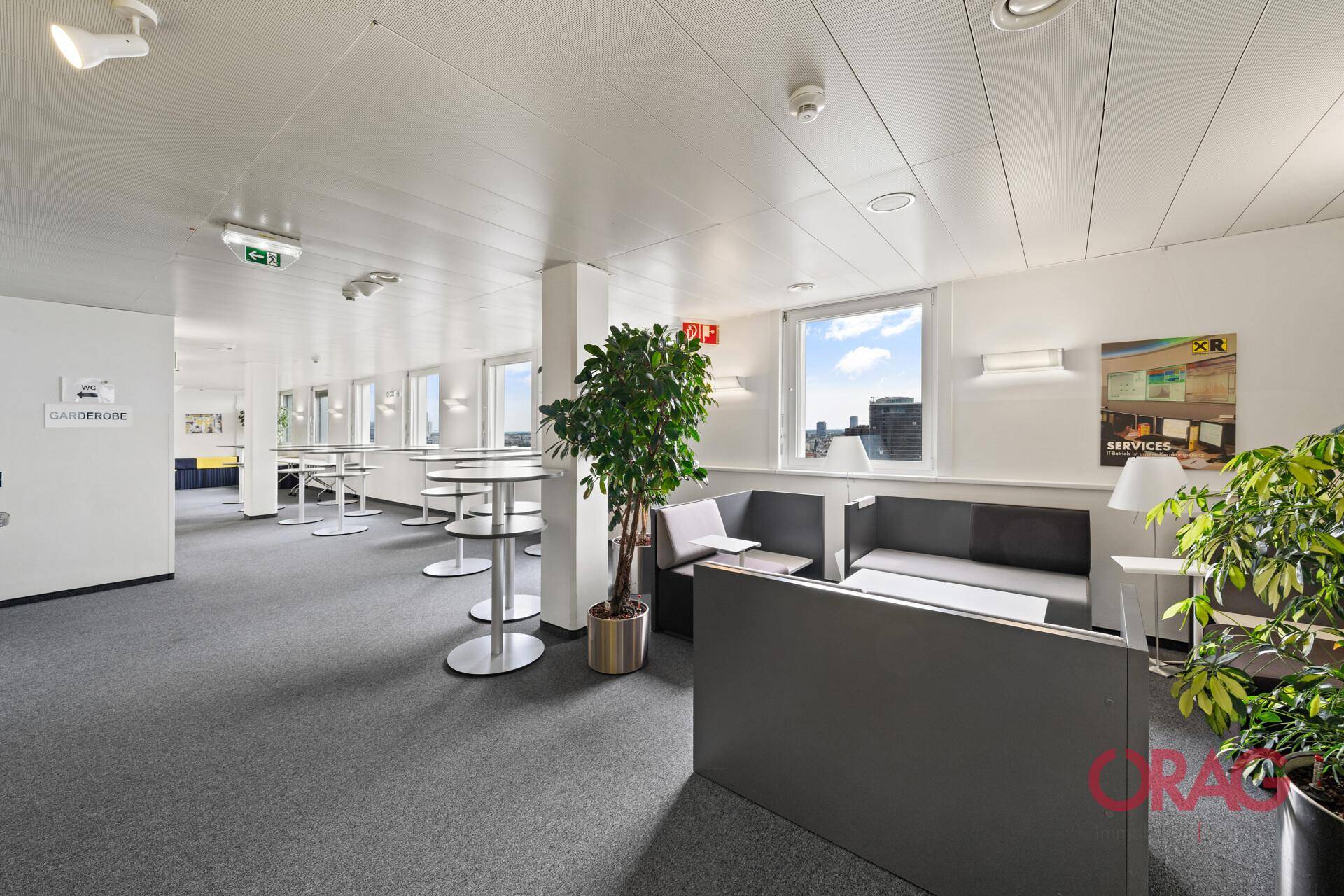 Geräumiger Loungebereich mit Sitzgelegenheiten, Stehtischen und Pflanzen für eine angenehme Atmosphäre.