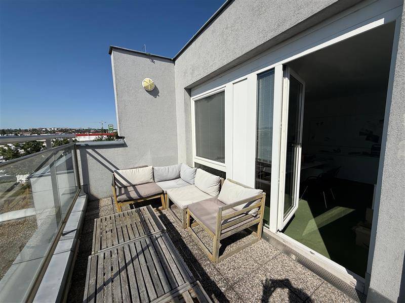 Sonnige Dachterrasse mit Loungemöbeln und Glasgeländer, ideal zum Entspannen im Freien mit Weitblick.