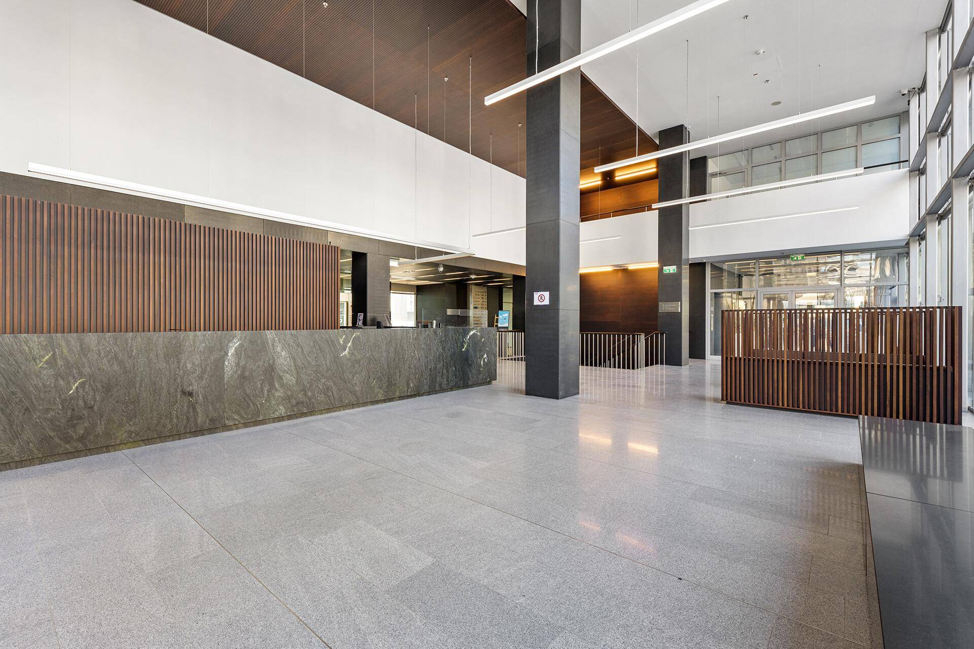 Elegante Lobby mit hoher Decke, Steinboden und einer langen Rezeption in modernem Design.
