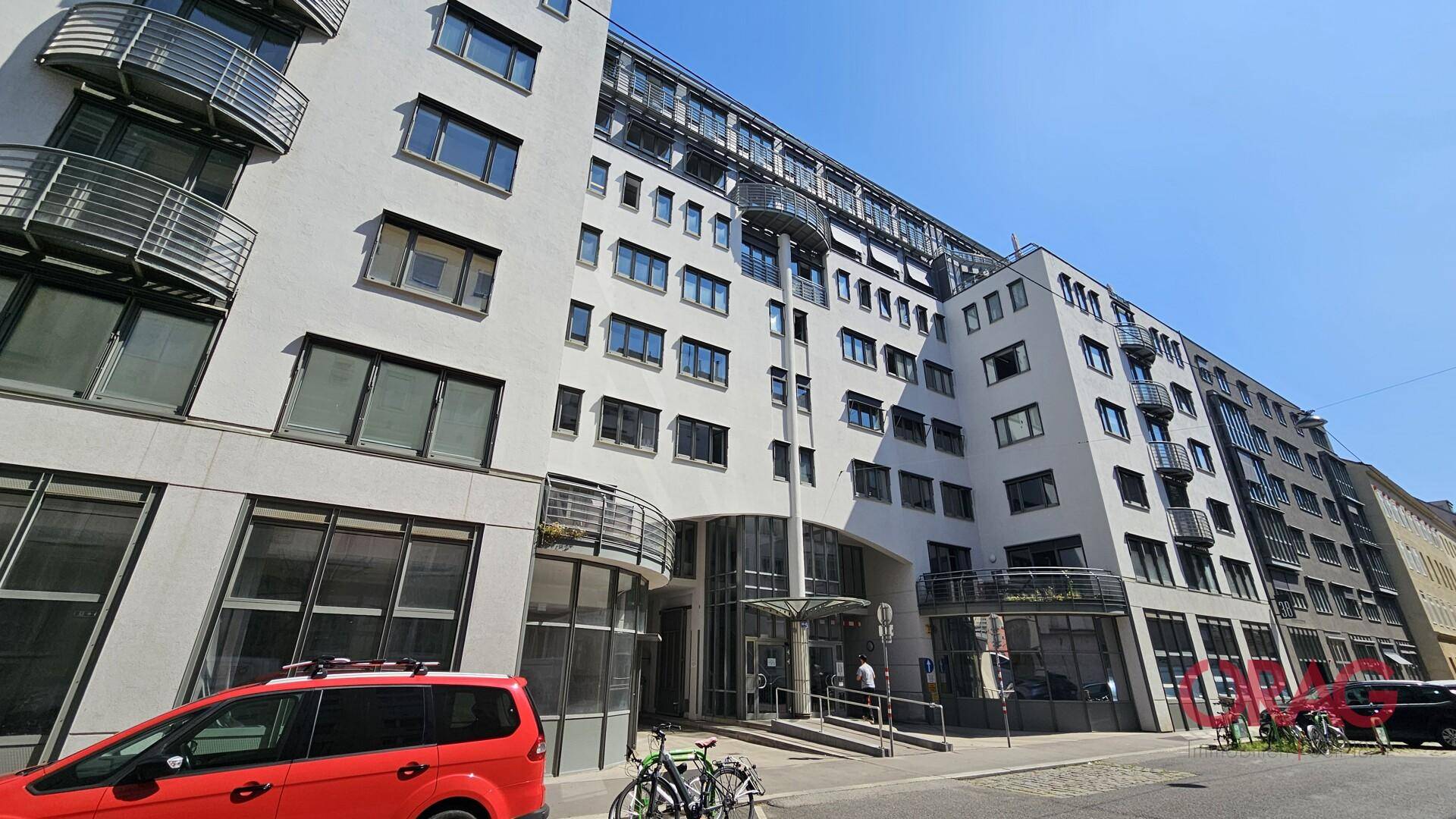 Moderne Bürogebäude-Fassade mit mehreren Balkonen und einem einladenden Eingangsbereich unter klarem Himmel.
