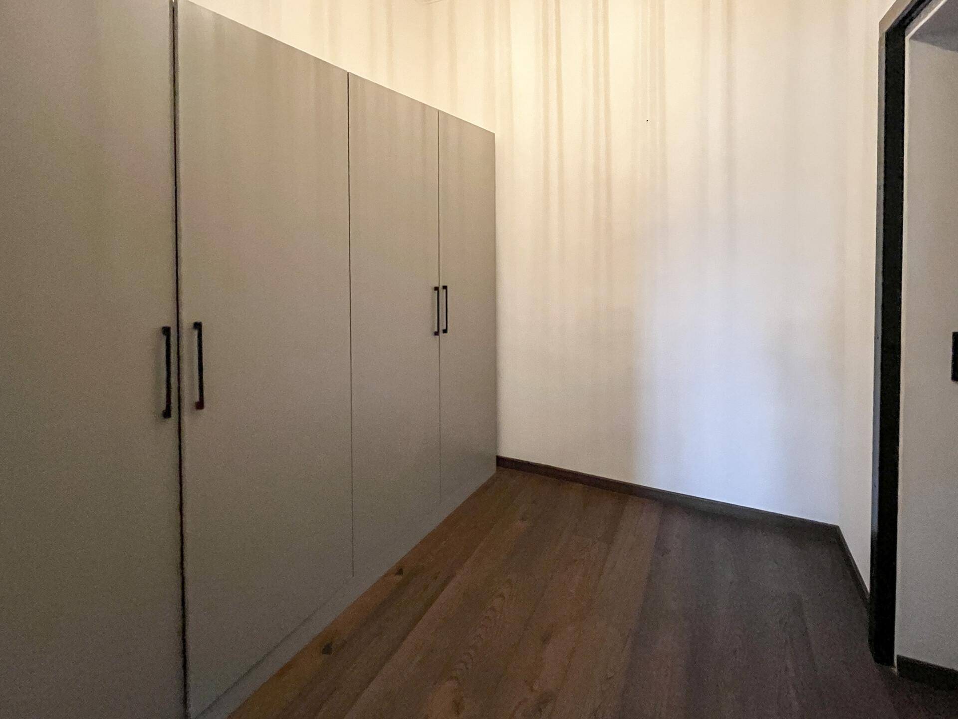 Heller Flur mit durchgehenden, modernen Einbauschränken und dunklem Holzfußboden.