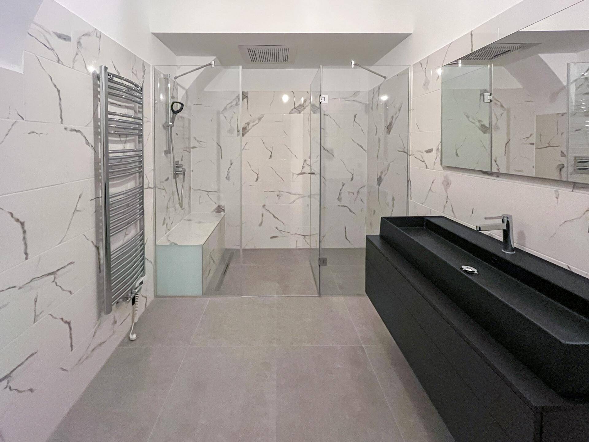 Geräumiges, modernes Badezimmer mit großer ebenerdiger Dusche, Marmorfliesen und beheiztem Handtuchhalter.