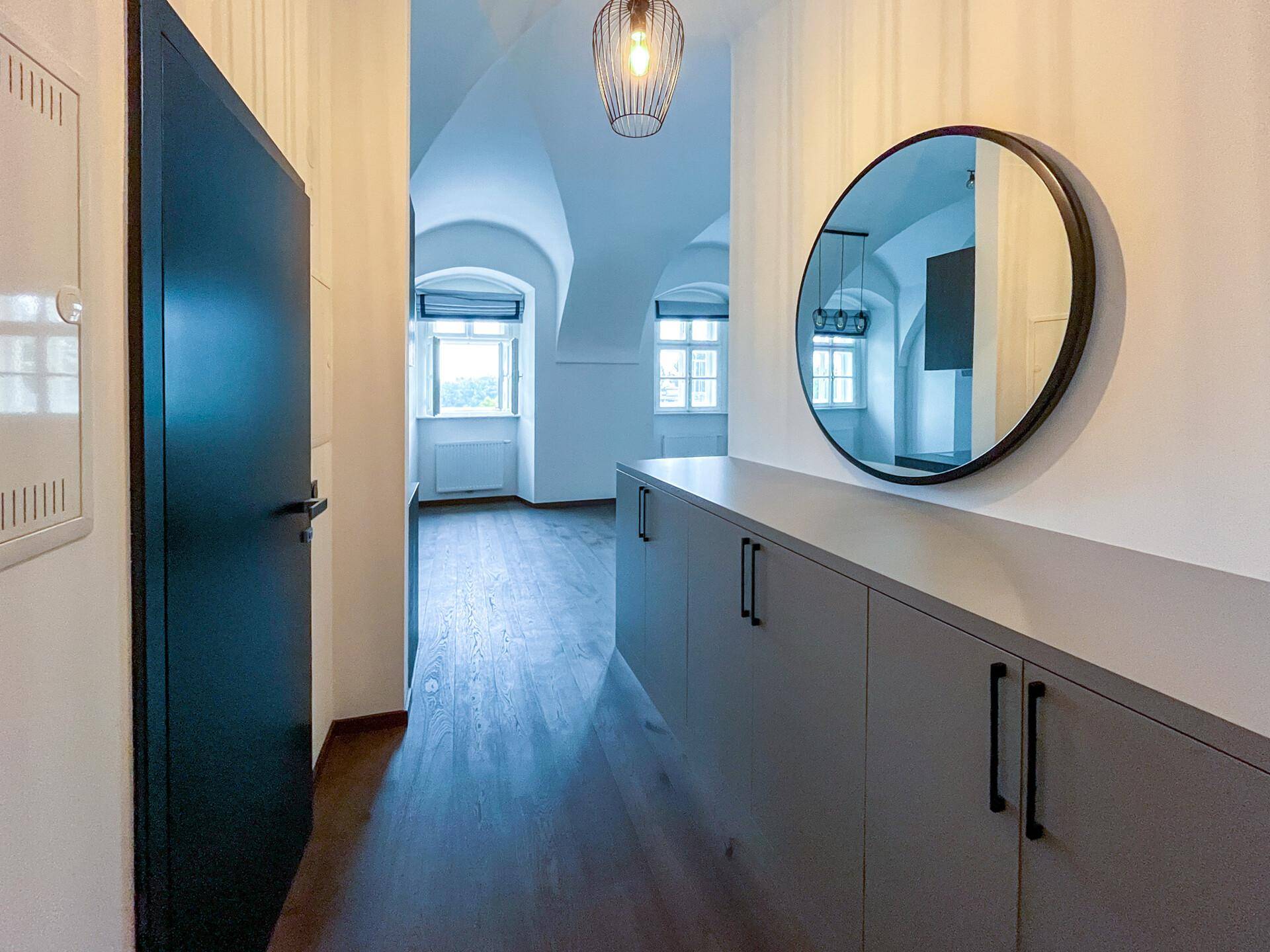 Heller Flur mit modernem Einbauschrank, rundem Spiegel und Blick in den Wohnbereich.
