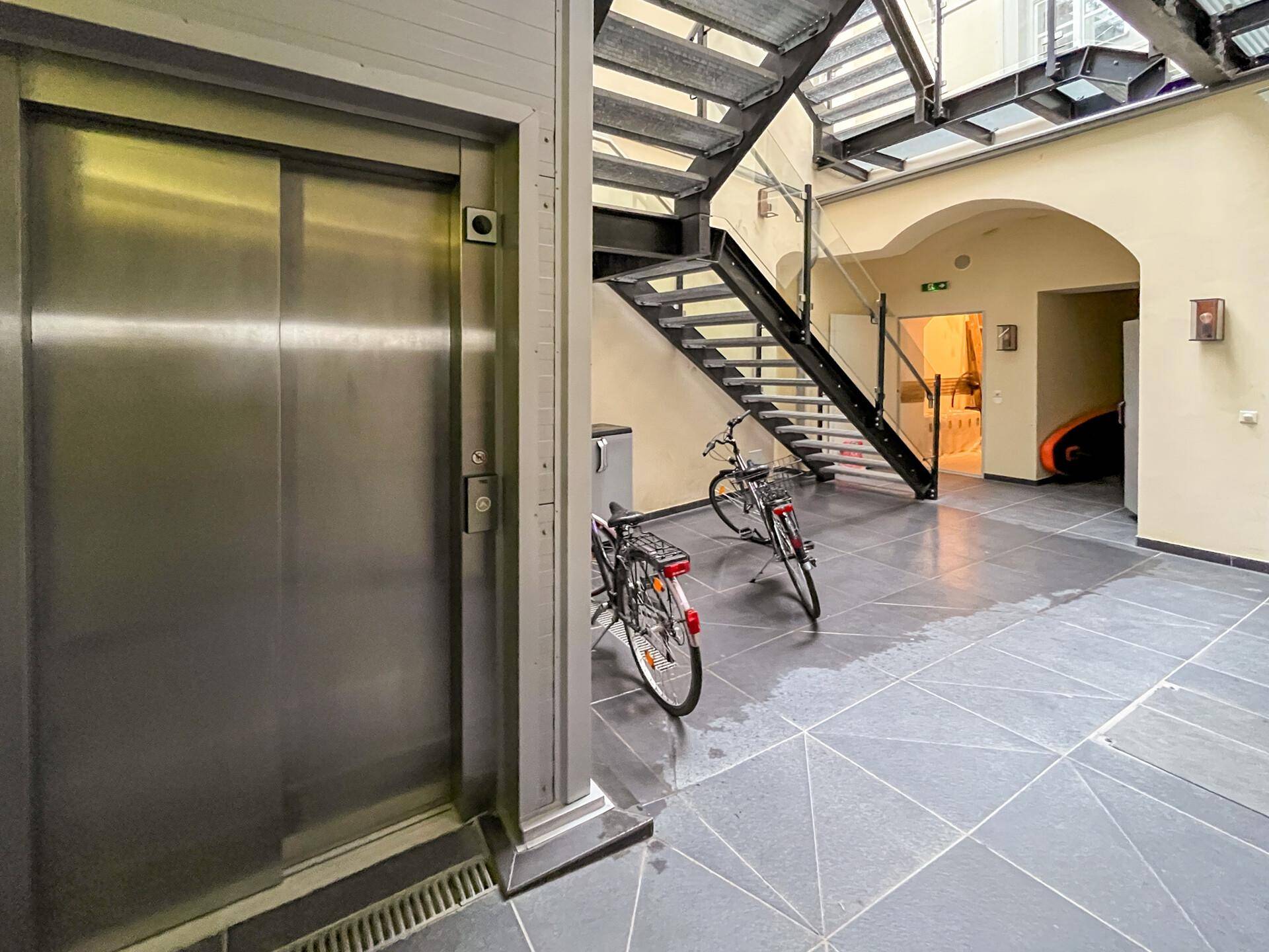 Heller Innenhof mit modernem Aufzug, Treppenhaus und Abstellmöglichkeiten für Fahrräder.