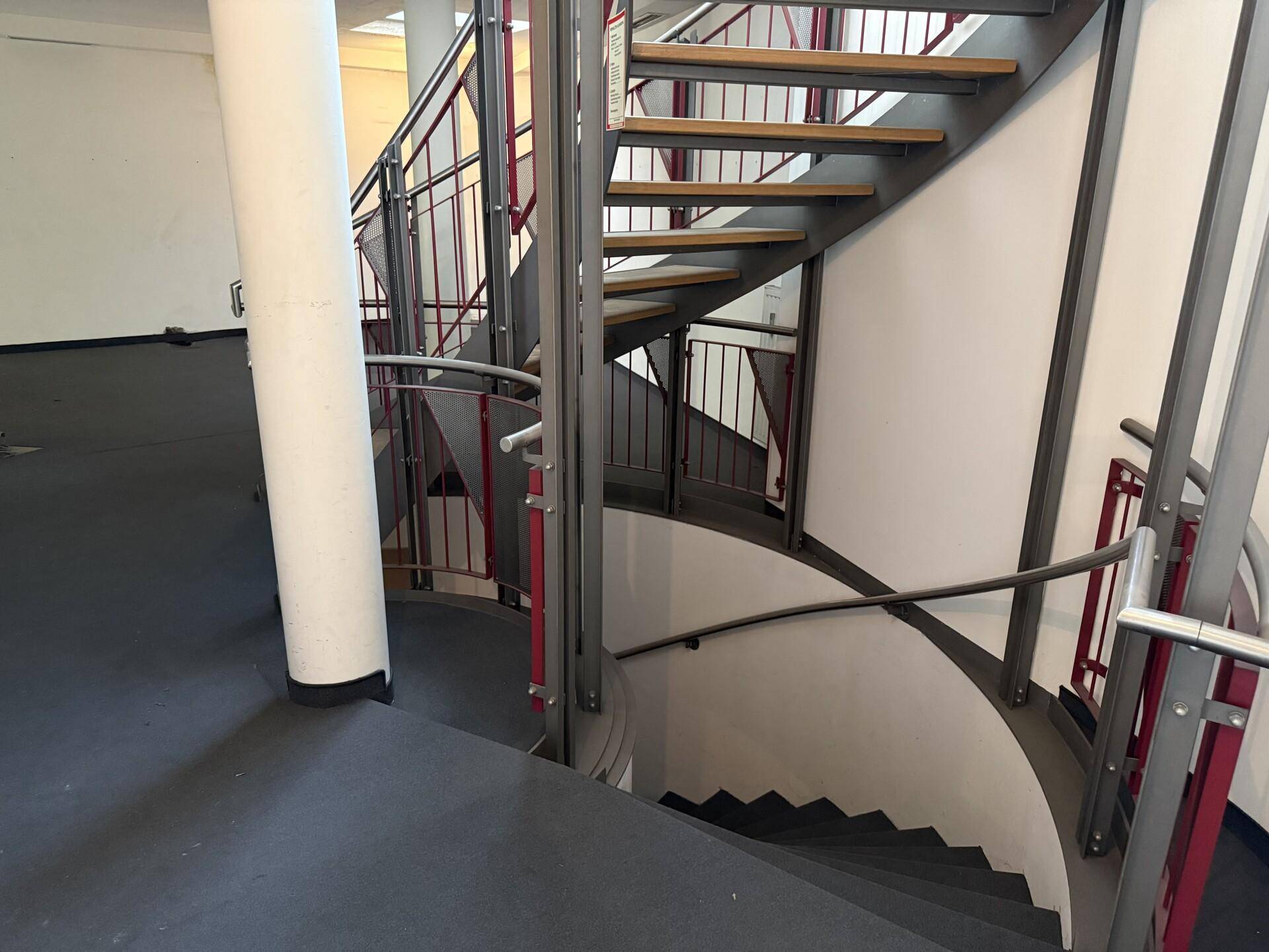 Elegante Wendeltreppe mit Holzstufen und Metallgeländer, die verschiedene Ebenen des Gebäudes stilvoll verbindet.