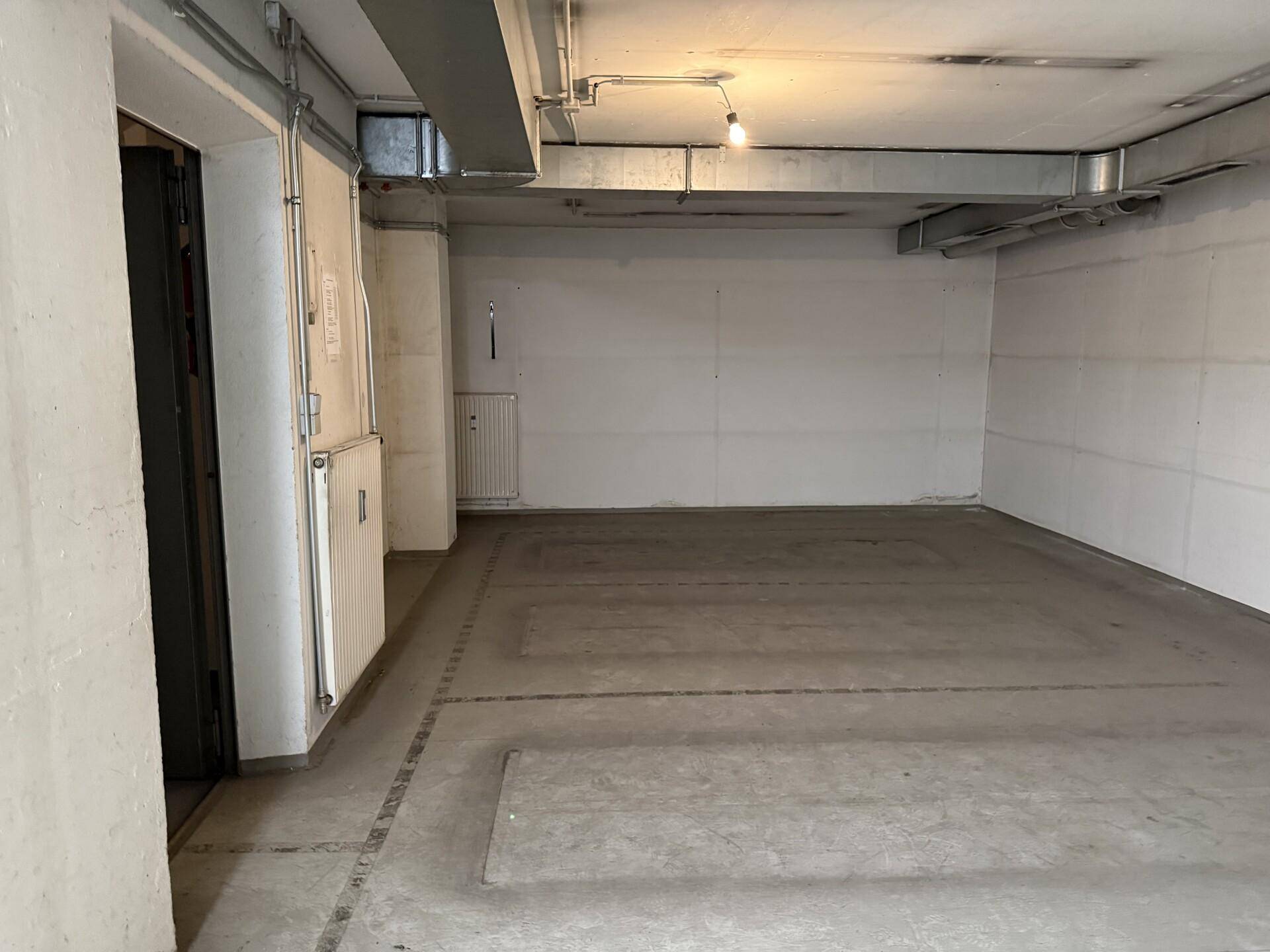 Funktionaler Kellerraum mit Betonboden, weißen Wänden und sichtbaren Deckeninstallationen, ideal als Lagerfläche.