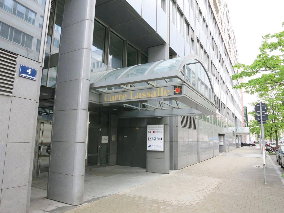 Eingangsbereich eines modernen Bürogebäudes namens "Carre Lassalle" mit Glasvordach und klaren Linien.