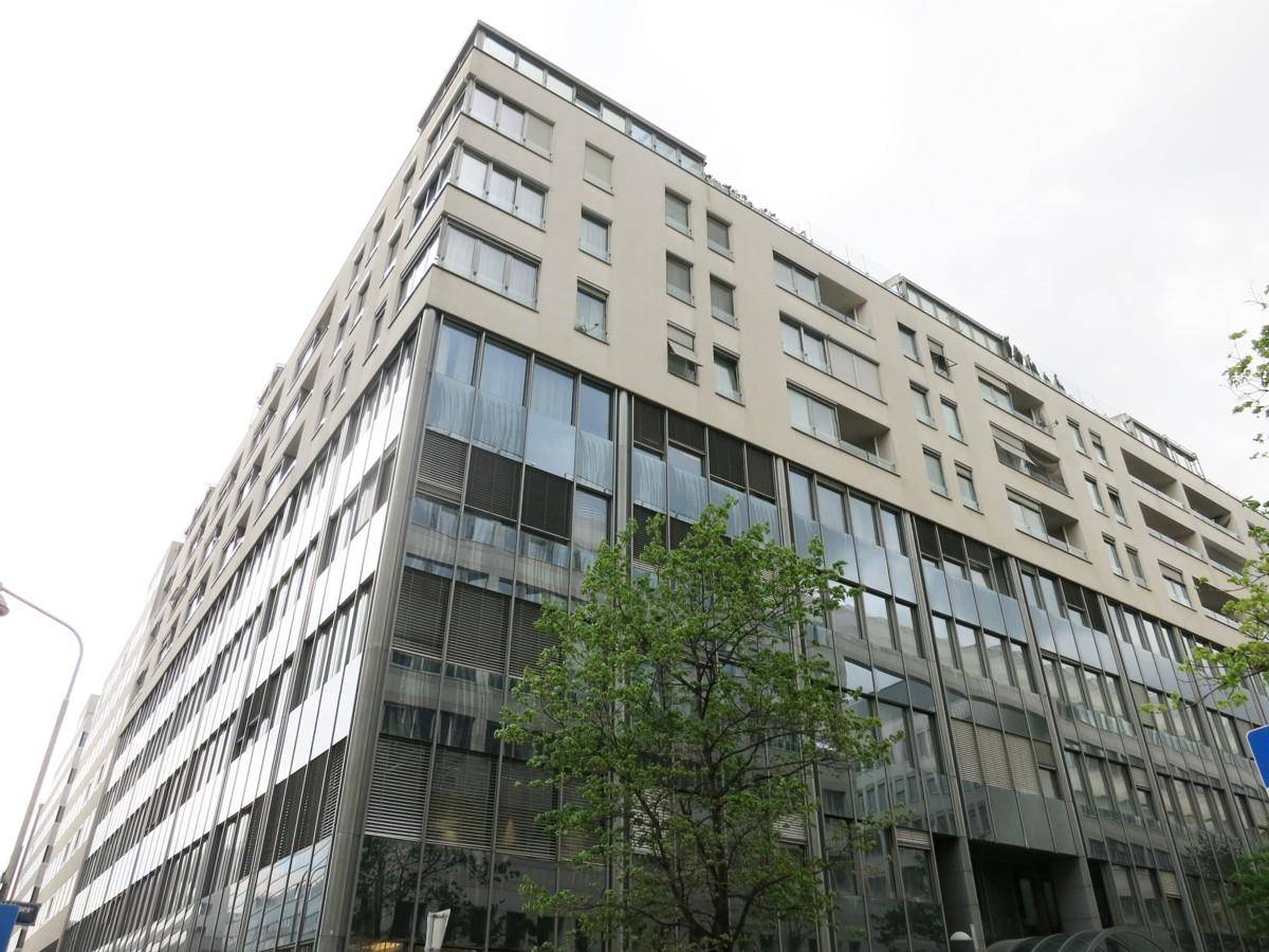 Architektonisch ansprechendes Gebäude mit einer Kombination aus Glasfassade und hellen Balkonen in den oberen Etagen.