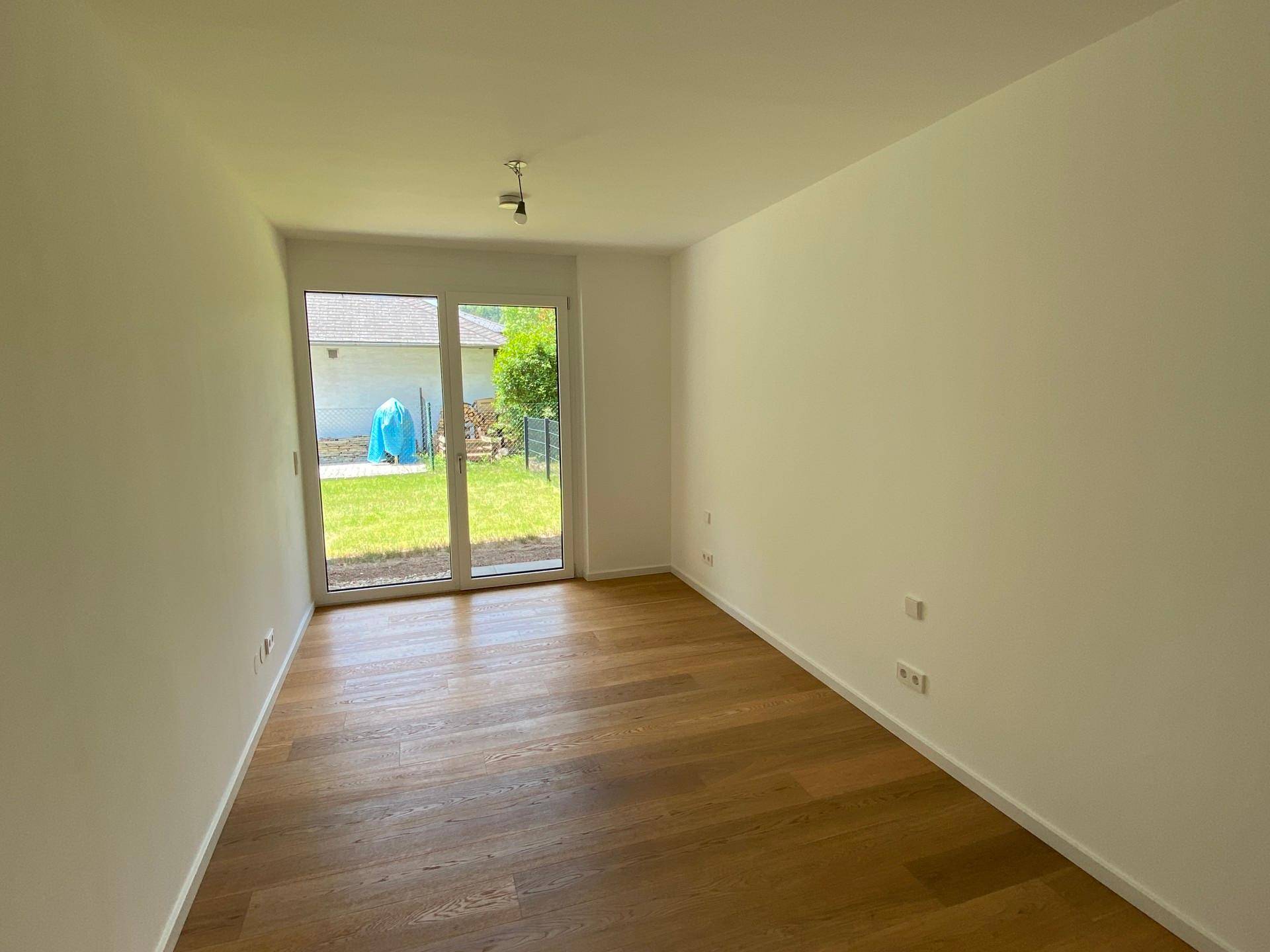 Helles Zimmer mit Holzboden und direktem Zugang zum Garten, ideal als Schlaf- oder Gästezimmer.