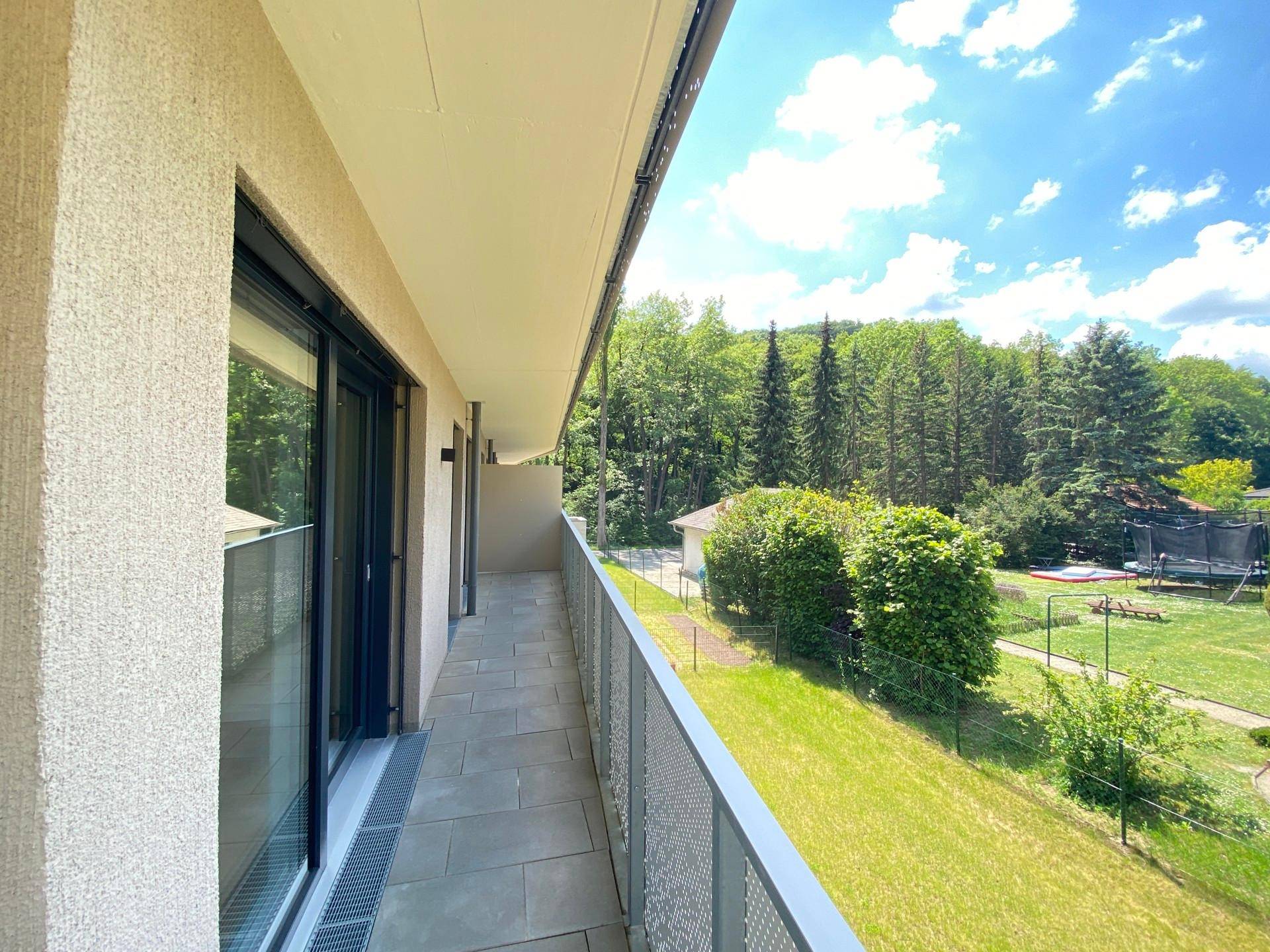 Langer Balkon mit Fliesenboden und weitem Blick auf die umliegende Natur und Bäume.